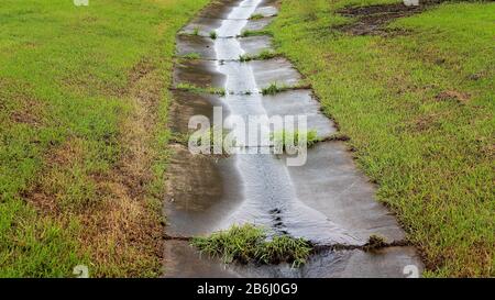 La lluvia tropical pesada hace que el agua fluya en el canal de drenaje Foto de stock