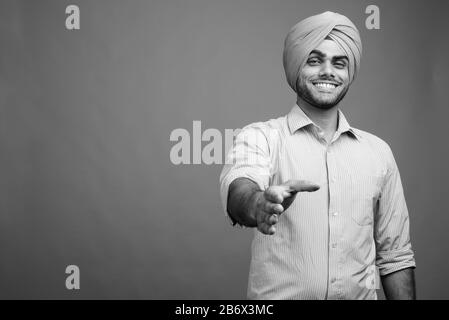 Joven hombre de negocios Sikh India guapo usando turbante contra fondo gris  Fotografía de stock - Alamy
