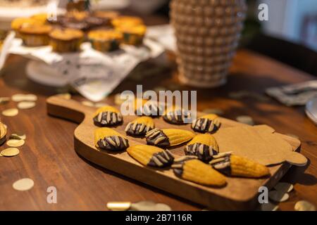 Petite Madeleines decorado como patas de oso con chocolate y almendras en una mesa. Foto de stock