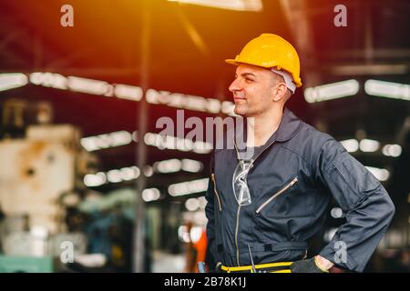 Trabajador feliz, retrato sonrisa trabajo guapo con traje de seguridad herramientas cinturón y el hombre de servicio de radio en la fábrica.