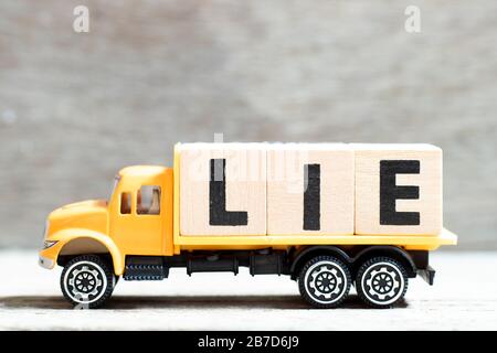 Camión mantener bloque de letras en la palabra mentira en el fondo de madera Foto de stock