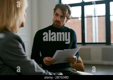 Retrato de cintura arriba de un hombre guapo con barba hablando con una compañera mientras se habla del trabajo en el interior de la oficina, espacio de copia