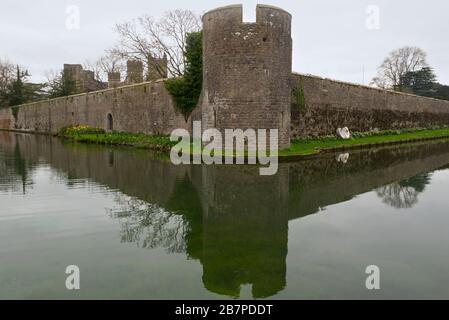 Mirando al otro lado del foso a las murallas del Palacio Episcopal en Wells, Somerset, Inglaterra, Reino Unido con las torres de la catedral en el fondo. Foto de stock