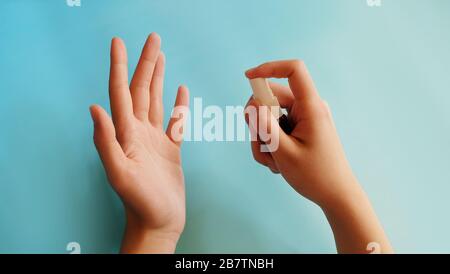 Una mano sosteniendo una pequeña botella de aerosol, rociando el contenido hacia la otra palma a cierta distancia. Foto de stock