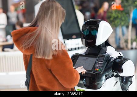 Mujer joven compradora y asesora de robots en la tienda Foto de stock