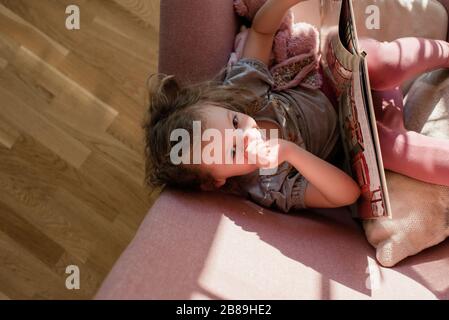 vista areal de una niña se sentó en una silla mirando hacia arriba en la lectura casera Foto de stock