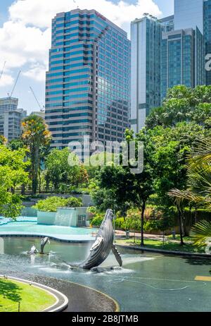 Torres de oficinas y fuente de escultura de ballenas en el Lago Symphony en el Parque KLCC Kuala Lumpur Malasia.