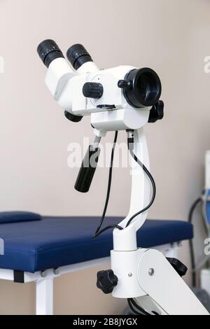 Sala ginecológica con silla y equipo. Manos de la doctora con herramientas para el examen de la salud de la mujer.