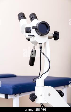 Sala ginecológica con silla y equipo. Manos de la doctora con herramientas para el examen de la salud de la mujer.