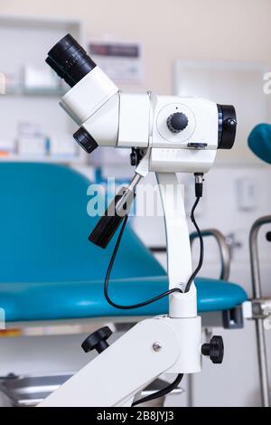 Sala ginecológica con silla y equipo. Manos de la doctora con herramientas para el examen de la salud de la mujer.