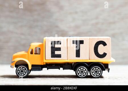 Carretilla mantener bloque de letras en la palabra etc (abreviatura de et cetera) sobre fondo de madera Foto de stock