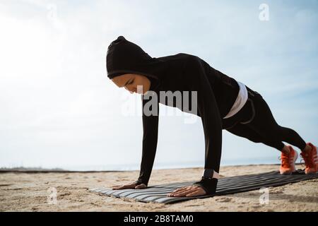 ajuste mujer musulmana haciendo empuje hacia arriba al aire libre. deporte mujer entrenamiento