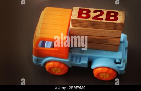 Toy Truck mantener bloque de letras en palabra B2B abreviatura de negocio a negocio sobre fondo negro. Concepto logístico B2B empresarial Foto de stock