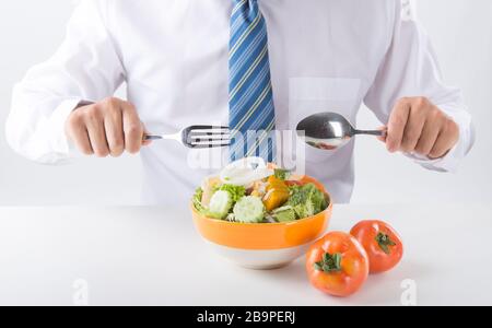 El empresario tiene una ensalada de verduras para comer, comer sano y el concepto de estilo de vida, persona irreconocible
