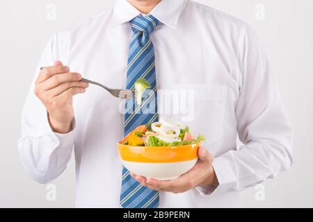El empresario tiene una ensalada de verduras para comer, comer sano y el concepto de estilo de vida, persona irreconocible