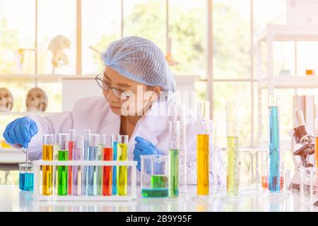 Una científica femenina asiática está investigando una fórmula química en un laboratorio.