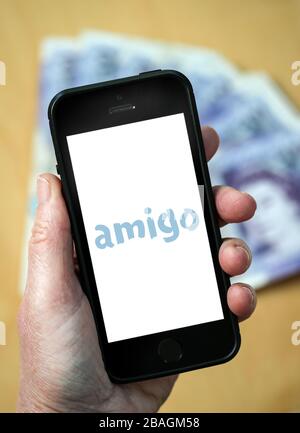 Una mujer mirando el logotipo de los préstamos de Amigo en un teléfono móvil. (Sólo para uso editorial) Foto de stock