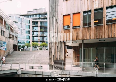 Oslo, Noruega - Junio 24, 2019: la gente caminando cerca de la zona residencial de casas de varios pisos en el barrio de Aker Brygge tarde de verano. Lugar famoso y popular. Foto de stock