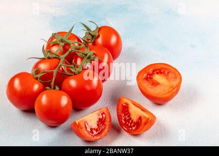 Tomates en rama (tomates de vid). Tomates sobre la vid y sobre un fondo de madera azul. Hermosos tomates con una hermosa rama verde.