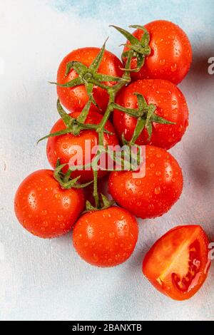 Tomates en rama (tomates de vid). Tomates sobre la vid y sobre un fondo de madera azul. Hermosos tomates con una hermosa rama verde.