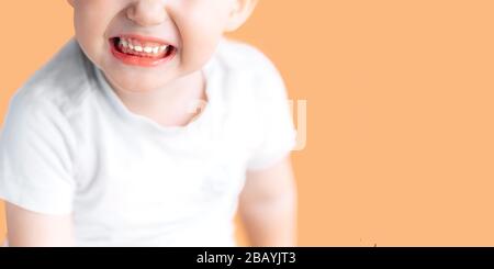 Un niño pequeño y hermoso se ríe mientras muestra sus dientes blancos