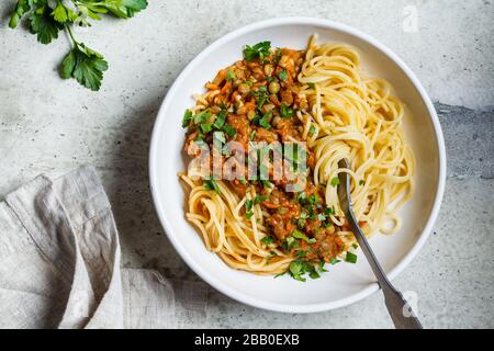 Lentejas vegetarianas pasta boloñesa con perejil en un plato blanco. Concepto de comida vegetariana saludable. Foto de stock