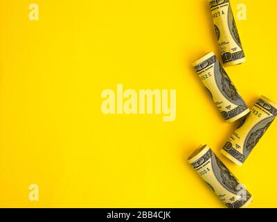 Dólares americanos en rollos. Concepto de ahorro de dinero sobre fondo amarillo con espacio de copia para texto Foto de stock