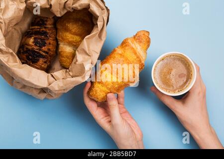Desayuno para llevar - cruasanes y café con leche sobre fondo azul. Vista superior Foto de stock