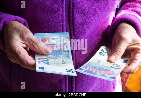 Las manos de la mujer son la celebración de unas monedas de euro. Pensión, la pobreza, los problemas sociales y el tema de la vejez. El ahorro. Foto de stock