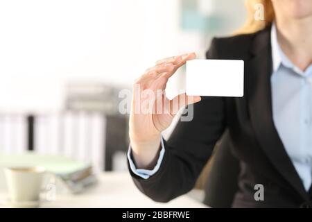 Primer plano de la mano de la mujer del negocio que muestra la tarjeta de crédito en blanco en la oficina