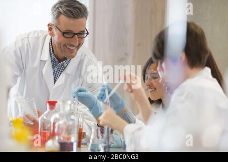 Profesor de ciencias masculino y estudiantes que realizan experimentos científicos en aulas de laboratorio Foto de stock