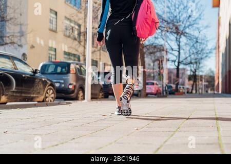 Mujer joven deportiva con prótesis de pierna caminando por la ciudad