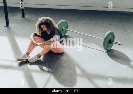 Mujer joven que se toma un descanso de hacer ejercicio en el gimnasio