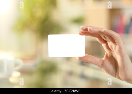 Primer plano de la mano de la mujer que muestra la tarjeta de crédito de la burla en casa