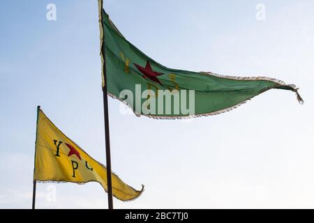Bandera que representa a las "unidades de Protección del Pueblo" lideradas por kurdos, más comúnmente conocidas como YPG y YPJ, vuelan en la ciudad de Qamishli, Siria. Foto de stock