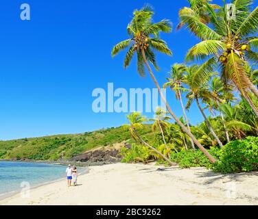Pareja caminando en una playa tropical, Isla Dramaqa, grupo de la isla Yasawa, Fiji, islas del Pacífico Sur, Pacífico Foto de stock