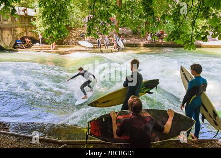 Surfistas en el Eisbachwelle en el río Eisbach, Jardín Inglés, Munich, Baviera, Alemania Foto de stock
