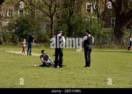 Londres, Hackney. Pandemia de coronavirus. Campos de Londres. Dos agentes de policía patrullan el parque advirtiendo a las personas que no ejercitan para seguir adelante. Foto de stock