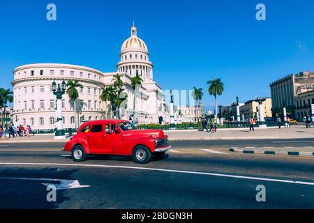LA HABANA, CUBA - 10 DE DICIEMBRE de 2019: Coches clásicos americanos de colores brillantes que sirven como taxis pasan en la calle principal frente al edificio Capitolio i