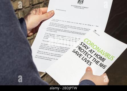 Londres / Reino Unido - 7 de abril de 2020 - persona que lee la carta de información sobre el coronavirus y el folleto del gobierno del Reino Unido, enviado a cada hogar durante la pa Foto de stock