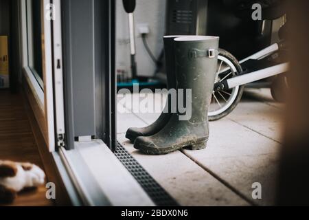 Un par de botas Muddy wellington en la alfombra de la puerta Foto de stock