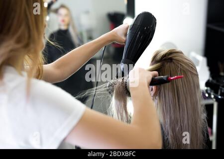 Secado de pelo largo rubio con secador de pelo y cepillo redondo Fotografía  de stock - Alamy