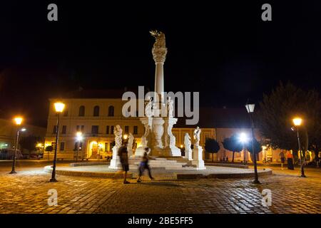 OSIJEK, CROACIA - 25 DE AGOSTO de 2017: Columna de la Santísima Trinidad en la Plaza Trg Svetog Trojstva en la Fortaleza de Osijek, llamada Tvrdja, por la noche, con la gente Foto de stock
