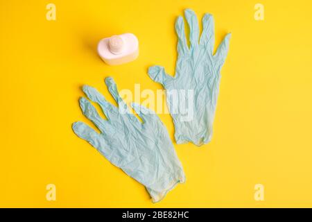 guantes de látex desechables y desinfectante en una superficie coloreada Foto de stock