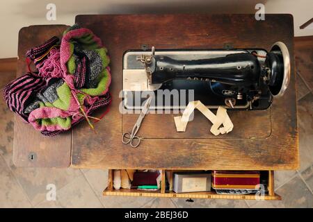 Vista superior de mesa de artesanía con máquina de coser vintage, tejidos y accesorios