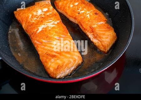 Filetes de salmón en sartén cocinar en placa de inducción. Primer plano. Foto de stock