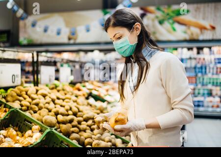 Mujer con máscara de compra segura de comestibles en medio de la pandemia de coronavirus en una tienda de comestibles.COVID-19 compra de alimentos en supermercado.Panic buyin