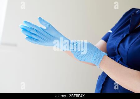 Enfermera poniéndose guantes de vinilo Foto de stock