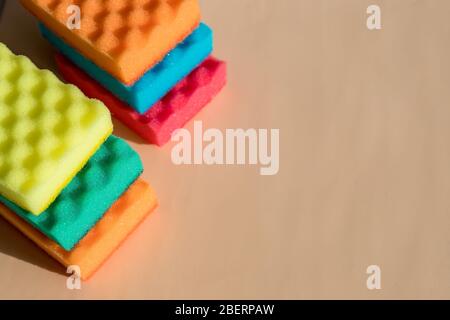 Esponjas de colores brillantes sobre fondo beige con esponjas de colores brillantes para lavar platos, limpiar el baño y otros hogares Foto de stock