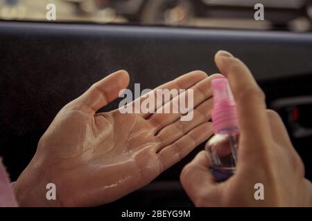 Desinfección de manos con un desinfectante a base de alcohol en un coche. Desinfección de manos después de usar el coche durante una epidemia. Foto de stock